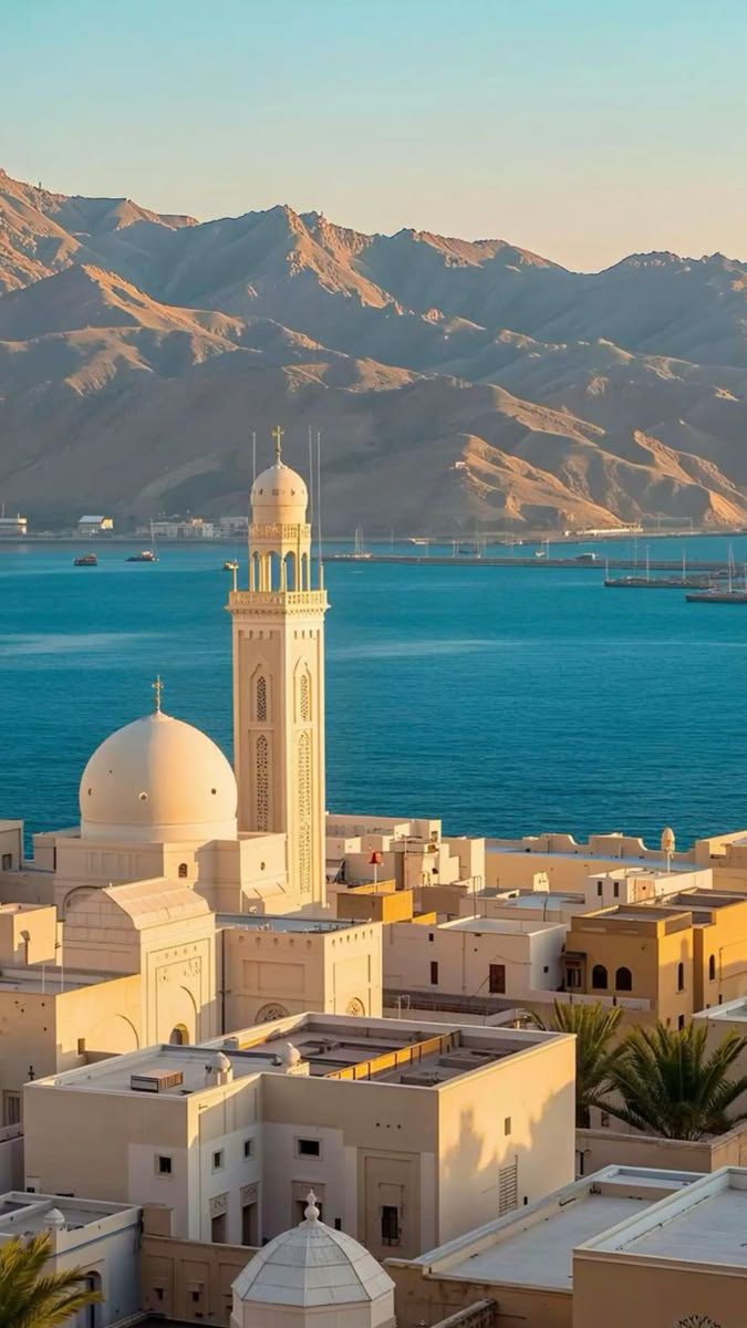 Mosque and harbour below desert mountains, Oman