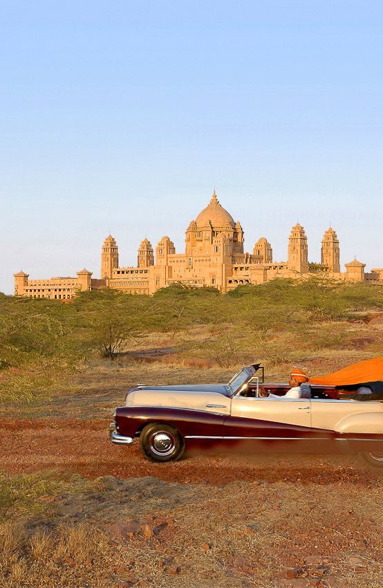 Vintage car below a Rajasthan palace