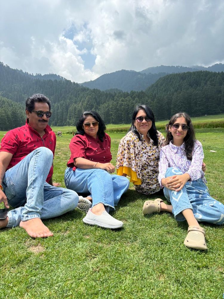 Family relaxing on a green meadow surrounded by pine forest